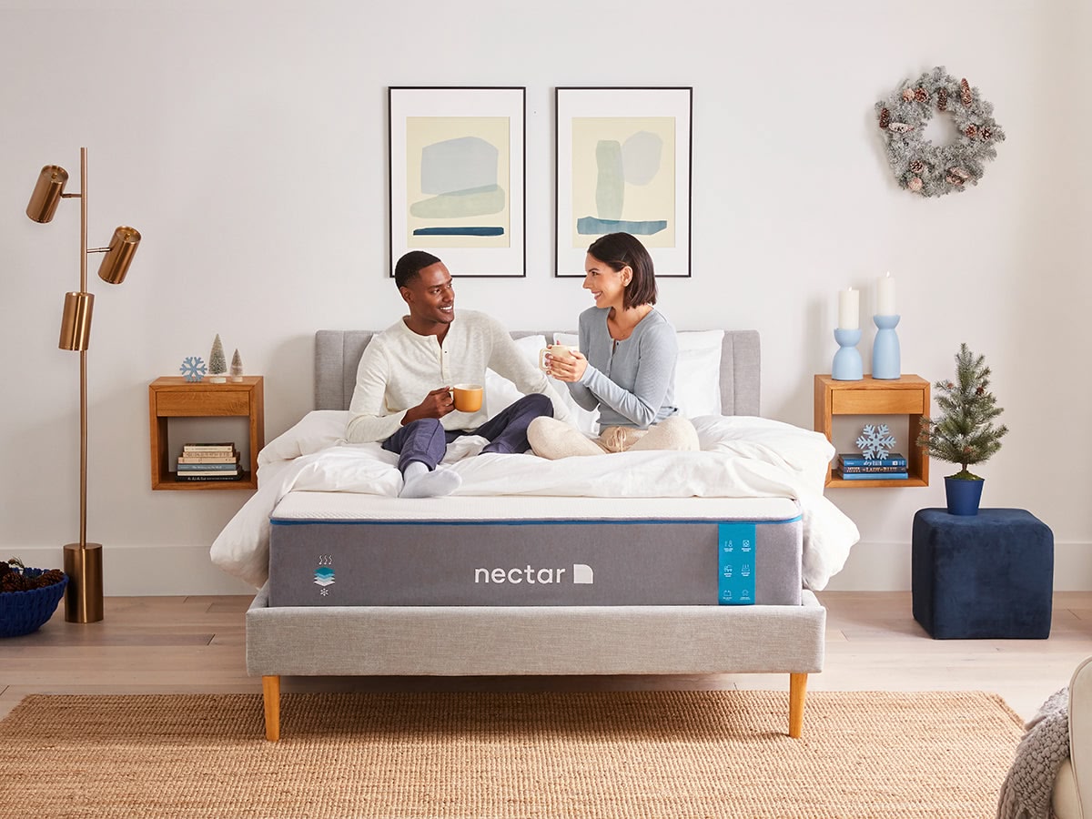 Couple sitting on a Nectar mattress in a bedroom setting